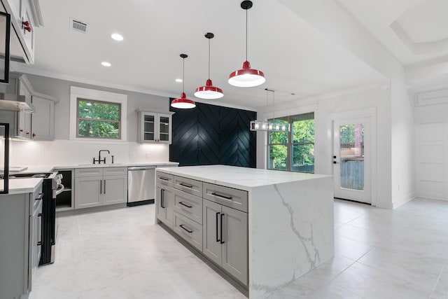 kitchen with a wealth of natural light, appliances with stainless steel finishes, a center island, and gray cabinetry