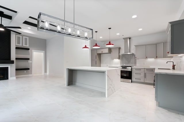 kitchen with wall chimney range hood, stainless steel stove, backsplash, and gray cabinetry