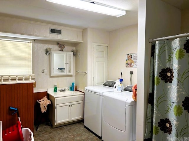 laundry room with sink, washing machine and dryer, and cabinets