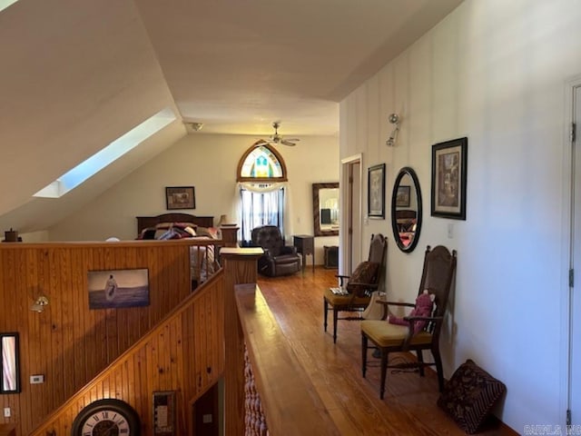 interior space with lofted ceiling, hardwood / wood-style floors, wooden walls, and ceiling fan