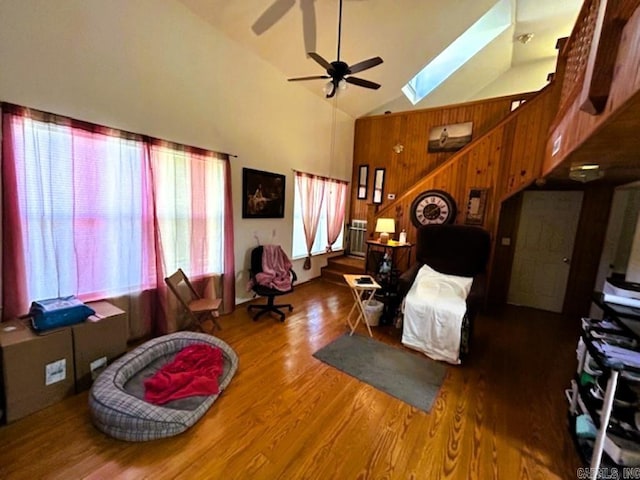 living room featuring a skylight, hardwood / wood-style flooring, high vaulted ceiling, and ceiling fan