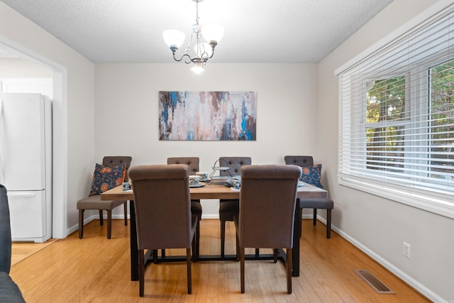 dining area featuring a textured ceiling, hardwood / wood-style flooring, and a chandelier