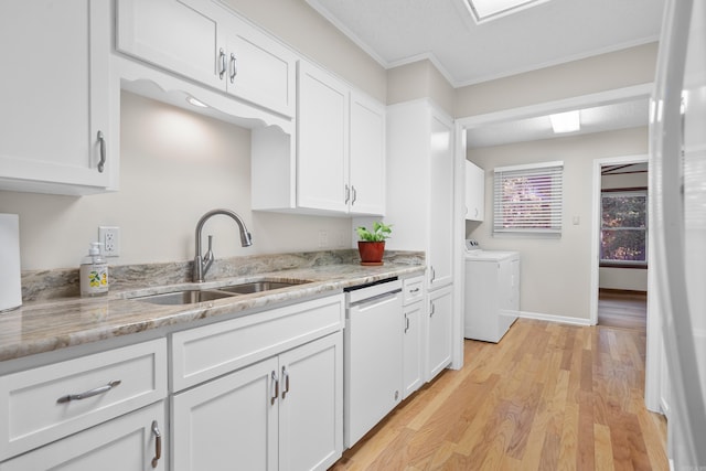 kitchen with white cabinetry, sink, white dishwasher, and washing machine and clothes dryer