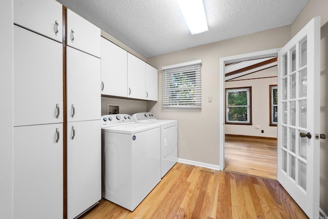 washroom featuring independent washer and dryer, a textured ceiling, light hardwood / wood-style floors, and cabinets