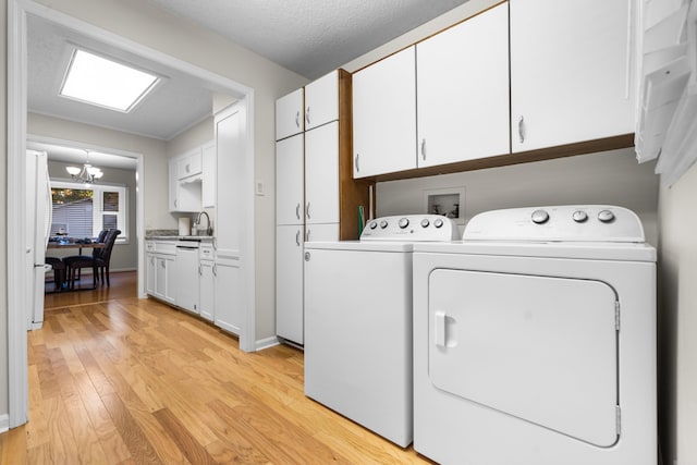 laundry area with sink, independent washer and dryer, light hardwood / wood-style floors, cabinets, and a chandelier