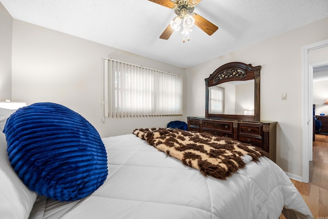 bedroom featuring light hardwood / wood-style floors, a textured ceiling, and ceiling fan