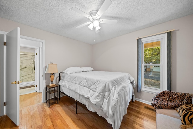 bedroom with a textured ceiling, light wood-type flooring, and ceiling fan