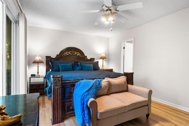 bedroom featuring multiple windows, a textured ceiling, light wood-type flooring, and ceiling fan