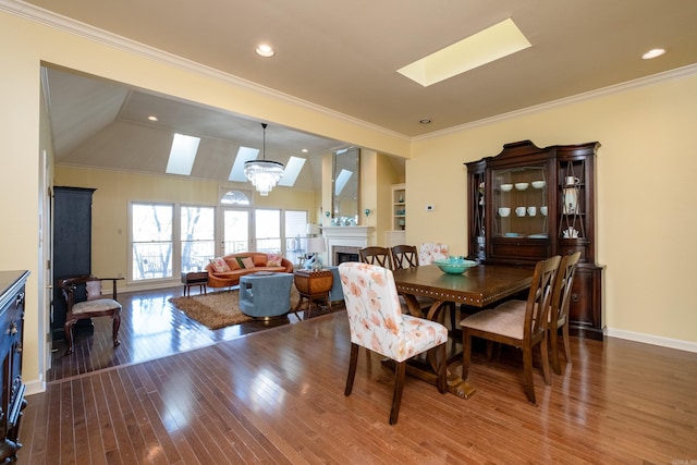 dining space featuring crown molding, lofted ceiling with skylight, a chandelier, and dark wood-type flooring