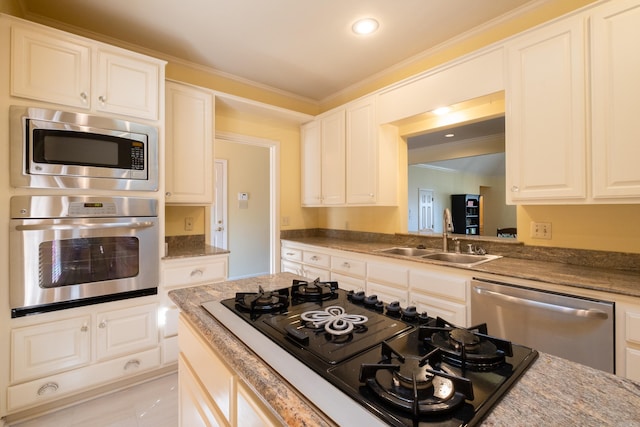 kitchen with white cabinetry, appliances with stainless steel finishes, sink, and ornamental molding