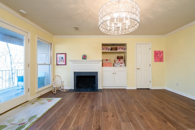 unfurnished living room featuring an inviting chandelier, crown molding, a tiled fireplace, and dark wood-type flooring