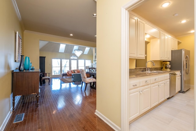 kitchen with white cabinets, ornamental molding, stainless steel appliances, light hardwood / wood-style floors, and sink