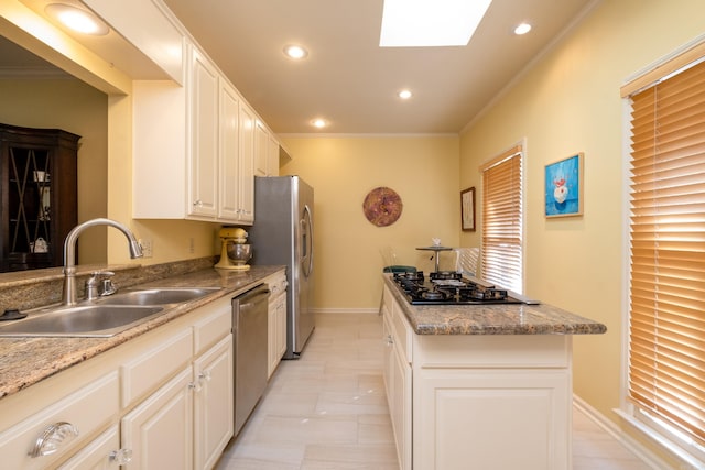 kitchen featuring sink, crown molding, white cabinets, appliances with stainless steel finishes, and a skylight