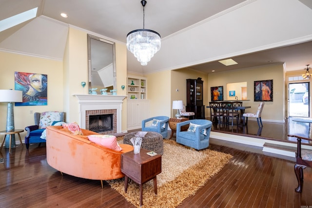 living room featuring dark wood-type flooring, crown molding, a brick fireplace, and a chandelier