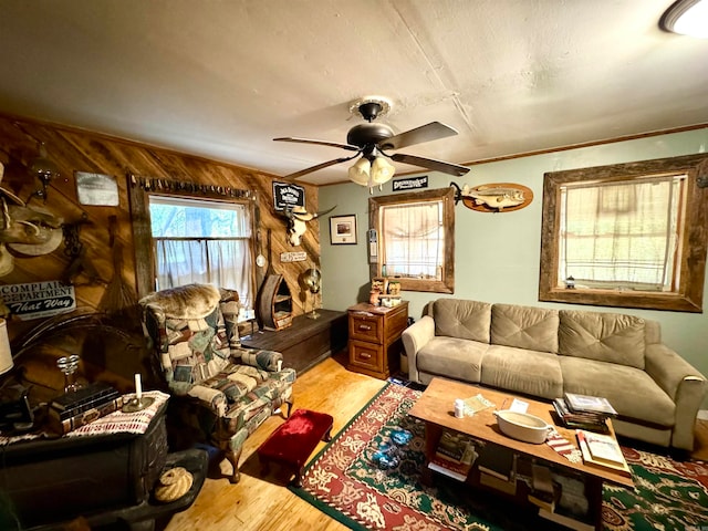 living room featuring light hardwood / wood-style flooring, ceiling fan, and wood walls