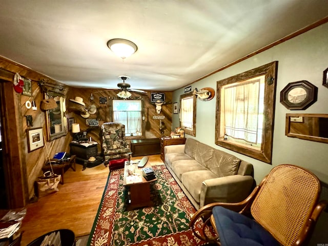 living room featuring wooden walls, wood-type flooring, and ceiling fan