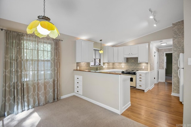 kitchen with white cabinets, light wood-type flooring, kitchen peninsula, vaulted ceiling, and high end stove