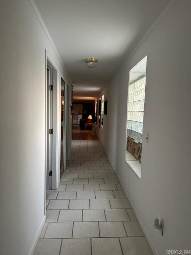 hallway featuring crown molding and light tile patterned flooring