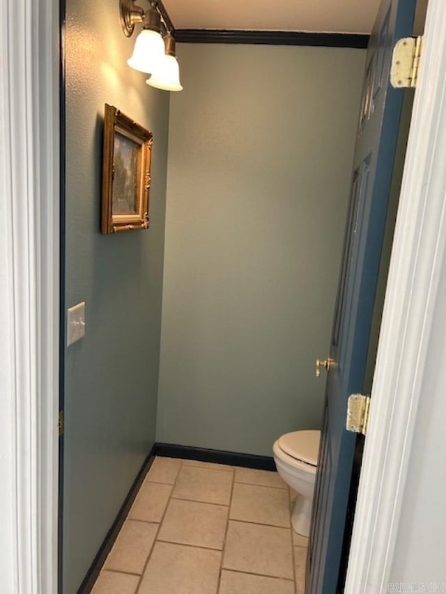 bathroom with tile patterned floors, crown molding, and toilet