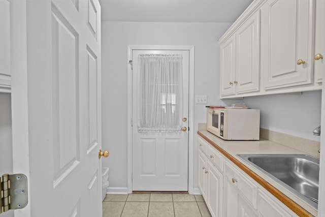 kitchen featuring sink, white cabinetry, and light tile patterned floors