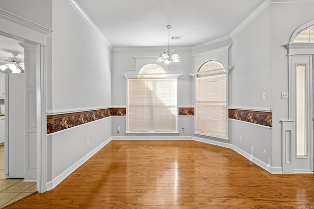 unfurnished dining area with crown molding, ceiling fan with notable chandelier, and light hardwood / wood-style floors