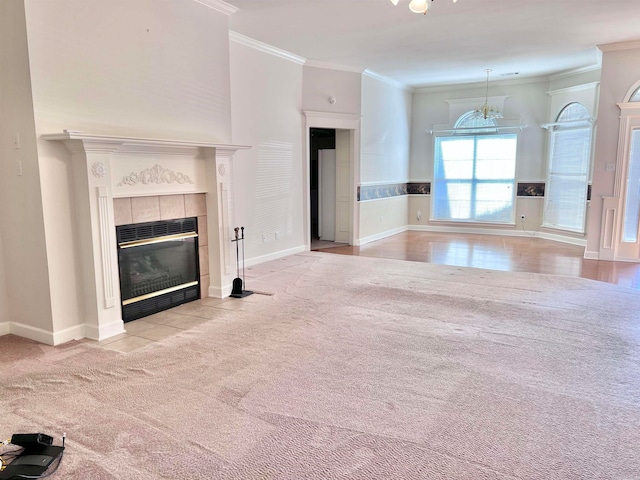 unfurnished living room with a notable chandelier, ornamental molding, a tiled fireplace, and light colored carpet