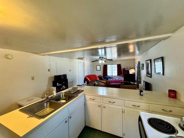 kitchen featuring kitchen peninsula, white cabinetry, sink, and ceiling fan