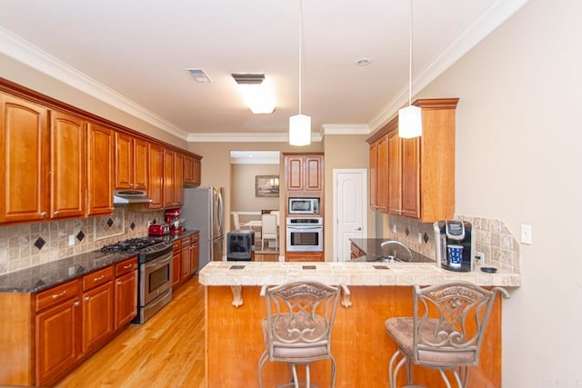 kitchen featuring appliances with stainless steel finishes, kitchen peninsula, and a kitchen bar