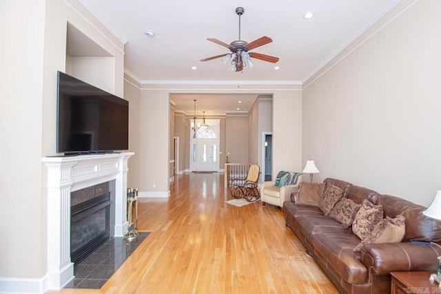 living room with crown molding, hardwood / wood-style floors, a tiled fireplace, and ceiling fan