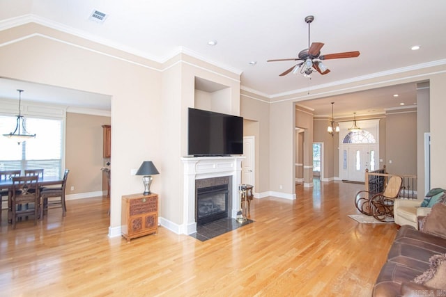 living room with a tiled fireplace, crown molding, and hardwood / wood-style flooring