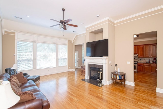 living room with light hardwood / wood-style floors, ornamental molding, and ceiling fan