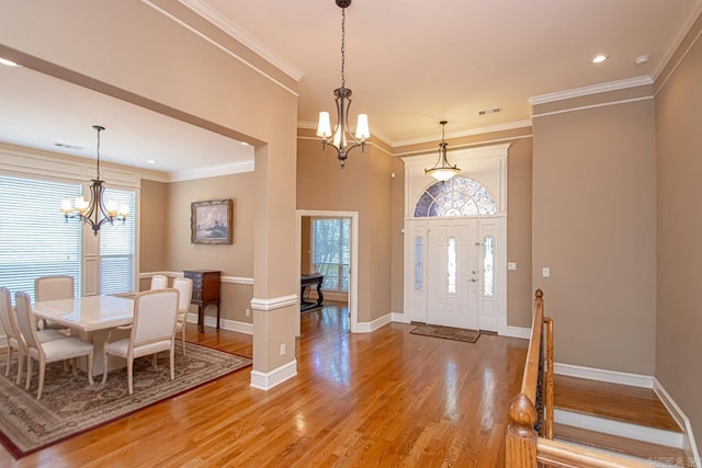 foyer with hardwood / wood-style flooring, ornamental molding, and a chandelier