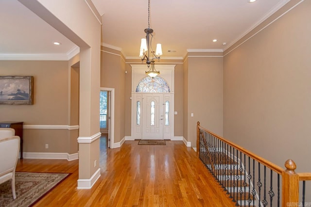 entryway featuring ornate columns, ornamental molding, a chandelier, and light wood-type flooring