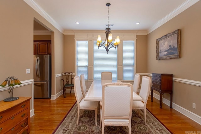 dining area with crown molding, hardwood / wood-style flooring, and a chandelier