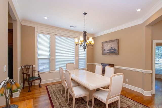 dining area with crown molding, hardwood / wood-style flooring, and a chandelier