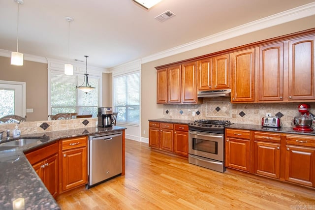 kitchen with light hardwood / wood-style floors, appliances with stainless steel finishes, ornamental molding, and hanging light fixtures