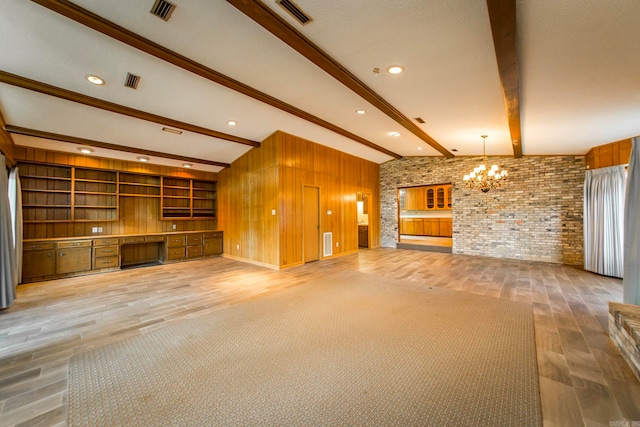 unfurnished living room with a notable chandelier, hardwood / wood-style floors, beamed ceiling, and wooden walls