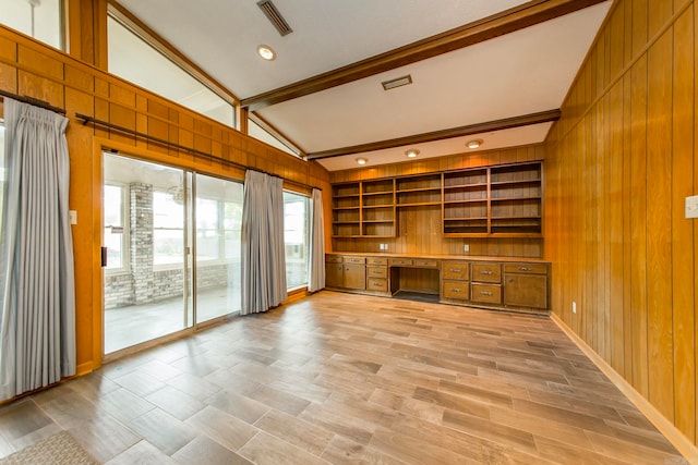 unfurnished living room featuring built in desk, light wood-type flooring, wood walls, and vaulted ceiling with beams