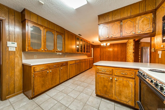 kitchen with white range with gas cooktop, wood walls, a textured ceiling, and light tile patterned floors