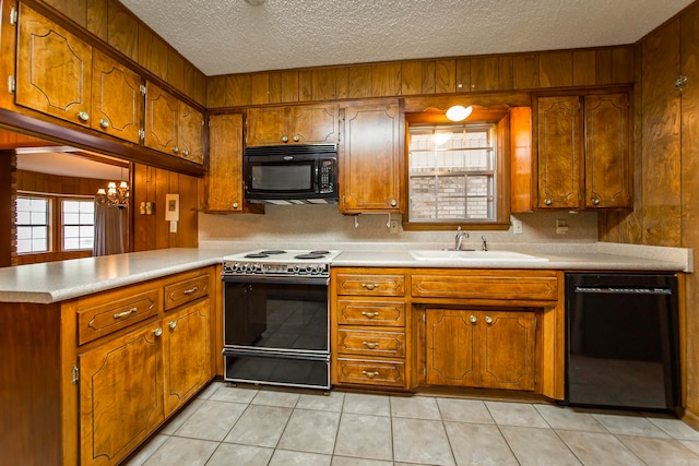 kitchen with kitchen peninsula, black appliances, light tile patterned floors, a textured ceiling, and wood walls