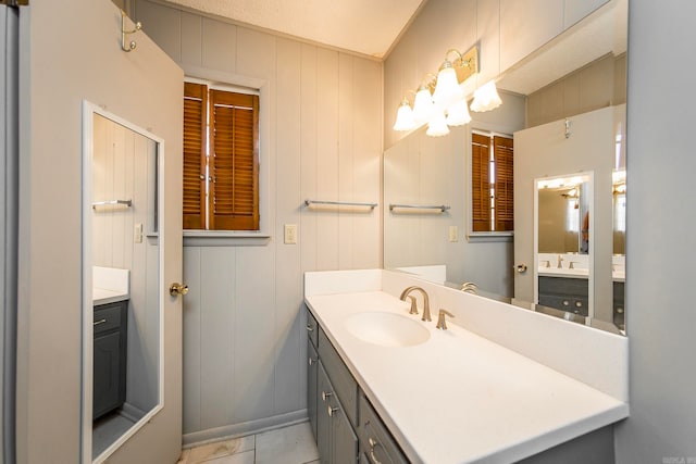 bathroom with wood walls, vanity, a textured ceiling, and tile patterned floors