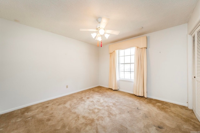 empty room featuring light carpet, a textured ceiling, and ceiling fan