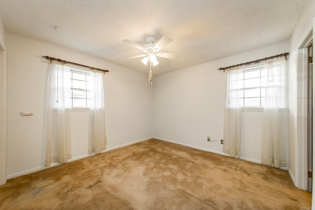 carpeted empty room featuring a wealth of natural light, a textured ceiling, and ceiling fan