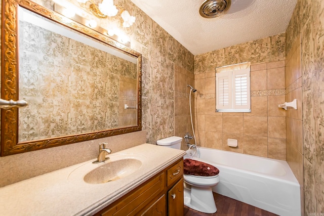 full bathroom with vanity, toilet, tiled shower / bath combo, and a textured ceiling