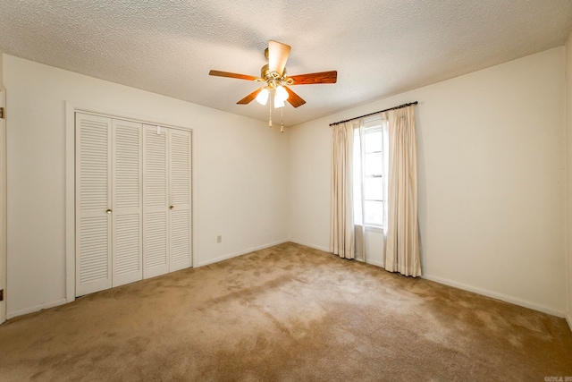 unfurnished bedroom with a textured ceiling, carpet flooring, a closet, and ceiling fan