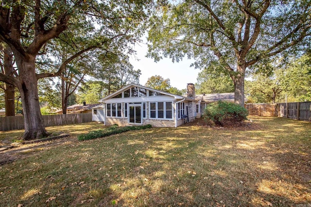 rear view of house featuring a sunroom and a lawn