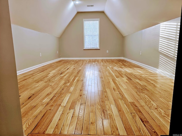 additional living space featuring lofted ceiling, baseboards, visible vents, and light wood-style floors