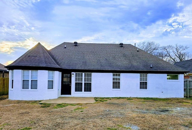 rear view of house featuring a shingled roof, a patio area, and fence