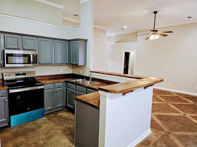 kitchen featuring crown molding, stainless steel appliances, wooden counters, a sink, and a peninsula