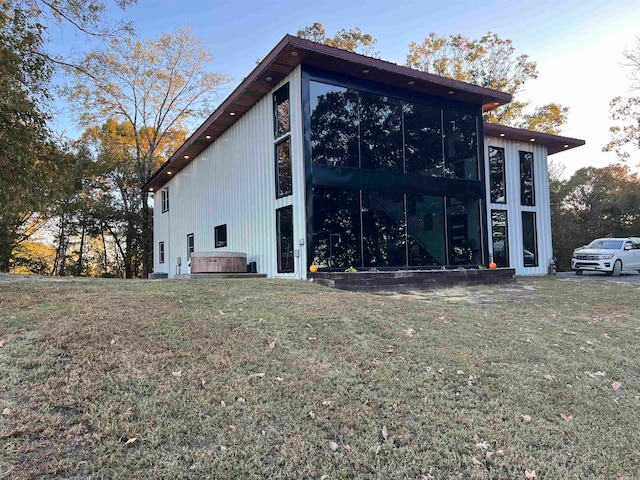 view of home's exterior with a sunroom and a lawn